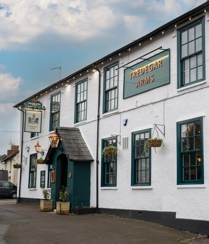 The exterior facade and signage of the Tredegar Arms in Bassaleg, with flower baskets hanging on the wall.