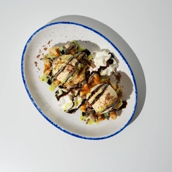 An overhead shot of a plated Pistachio & Chocolate Waffle against a white background.