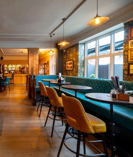 The interior restaurant seating area at The Talbot in Worcester; with upholstered chairs, benches, and booth seating; a TV on the wall; and a gaming machine.
