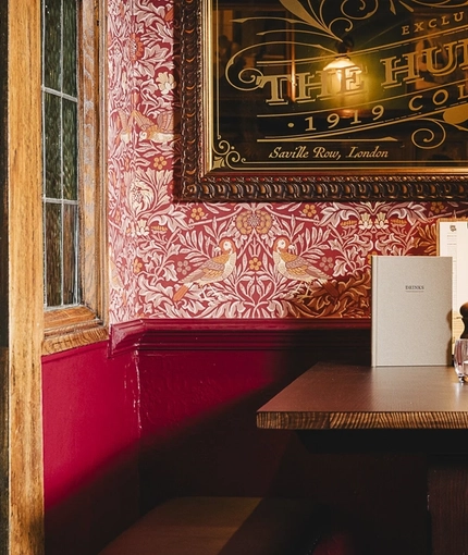 An interior restaurant seating area at the Masons Arms, with upholstered benches, and wood panelling on the walls.