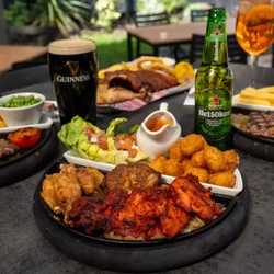 A plate of Tikka Tandoori on a beer garden table, surrounded by drinks and food.