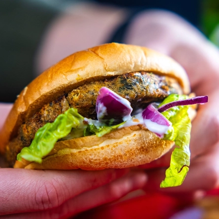 Hands holding a burger.