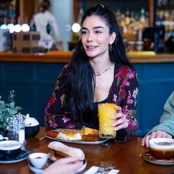 An image focusing on a person sat with a group of people at a table within the restaurant area with a breakfast dishes and drinks available at Urban Social venues.