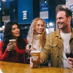 A lifestyle image of 4 friends stood at the bar enjoying various drinks within the interior of an Urban Core Venue.