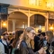 An image focusing on 2 friends enjoying glasses of white wine and celebrating with a cheers stood outside The Kings Stores.