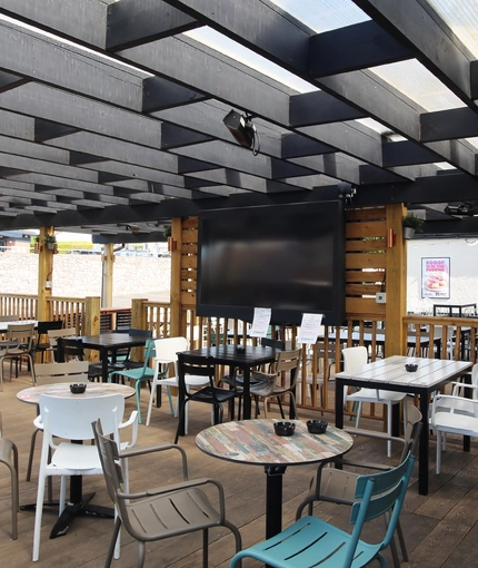 Exterior semi-open dining area of a pub with a TV.