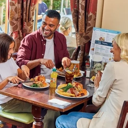 family sitting round a table in a restaurant eating a roast dinner