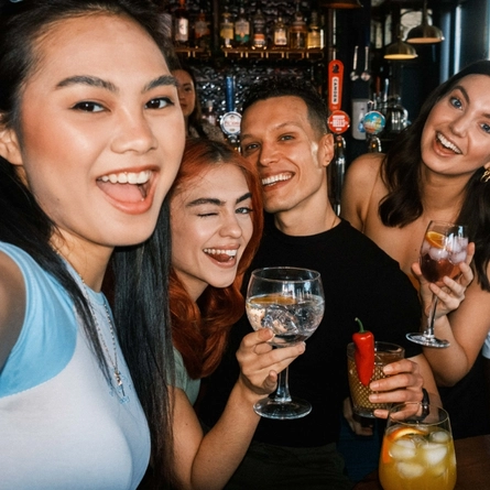 A group of people posing for a selfie with drinks in their hands.