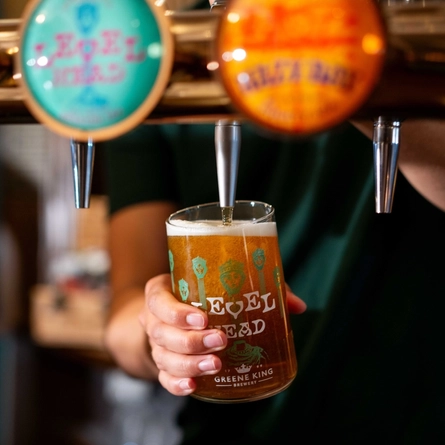 A close up image of a pint of Level Head being poured behind the interior bar at a Community Pubs With Food venue.