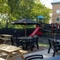 The exterior beer garden seating area with tables, chairs, wooden bench seating, children's play area and string lighting at The Castle View.
