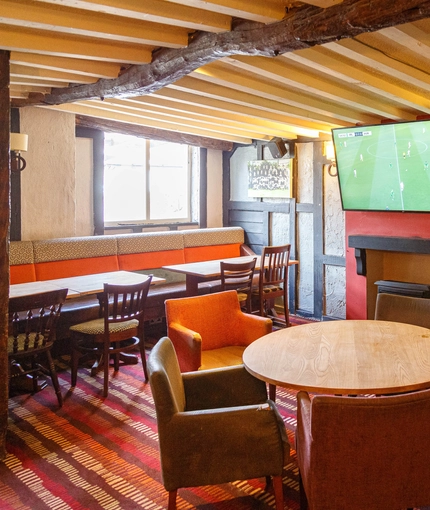 Interior dining area of a pub with a TV and a fireplace.