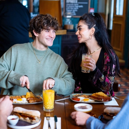 An image of a group of people sat at a table within the restaurant area with a breakfast dishes and drinks available at Urban Social venues.