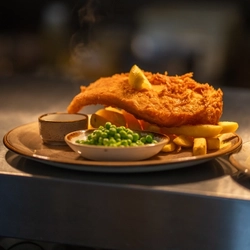 An image of a plated fish, chips and peas dish sat on an interior food counter cabinet at a Chef & Brewer venue.