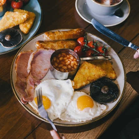A lifestyle image showing 2 customers enjoying Full English Breakfast's with coffee and fruit juice within the interior restaurant seating area at Urban Core Venues.