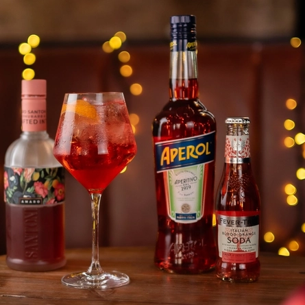 a glass of wine and a few bottles sitting on a wooden table of a pub