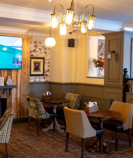 Interior dining area of a pub with a fireplace and a TV playing sports.