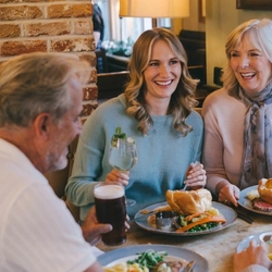 An image focusing on 2 family members sat within a group enjoying Mothers Day main dishes and drinks within the interior restaurant seating area at a Pub & Grill venue.