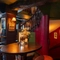 The interior restaurant and seating area focusing on a table positioned next to a set of stairs going up and down with a sign that says 'Down to gents' and points down the stairs at the Three jolly Butchers.