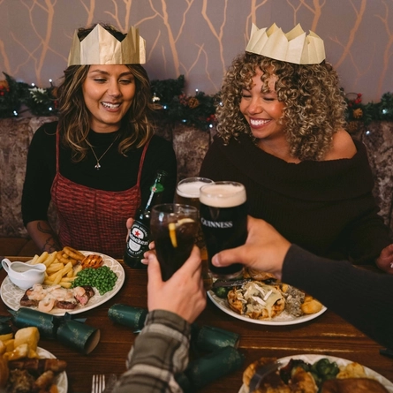 A group of people seated at a festive decorated table  with plated meals and drinks in front of them.