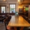 An interior restaurant seating area at The Woolpack Inn; with wooden flooring, an upholstered booth seat against the windows, and large TVs on the walls.