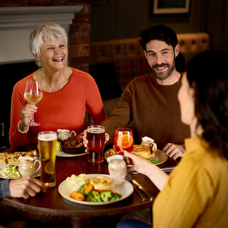 An image of 4 customers enjoying mains dishes and various drinks within the interior restaurant and seating area at a Chef & Brewer venue.