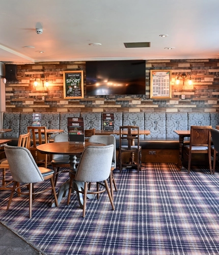 Interior dining area of a pub with a TV and a gambling machine.