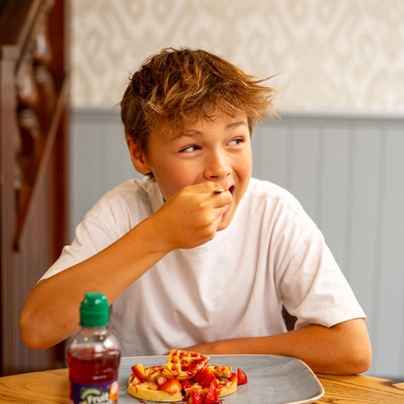 An image of a boy enjoying a waffle dessert and drink within the interior restaurant and seating area at a Hungry Horse venue.