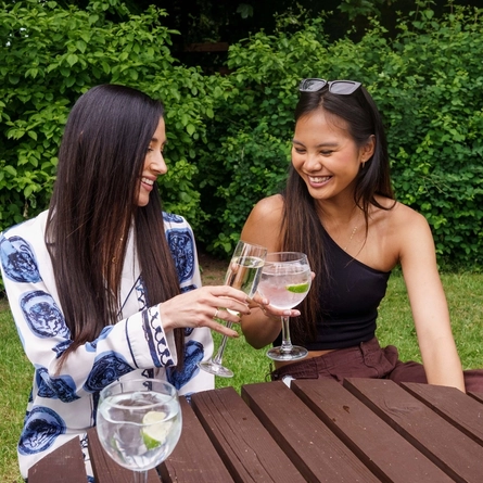 An image showing people sat enjoying various drinks within an exterior beer garden seating area.