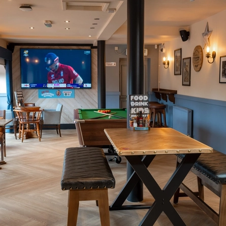 An interior restaurant seating area at the Cuckoo Oak, with a TV on the wall and a pool table.