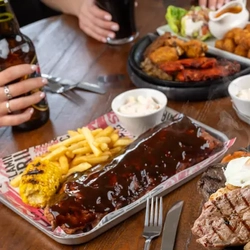 A rack of ribs, served with fries, on a table surrounded by other meals.