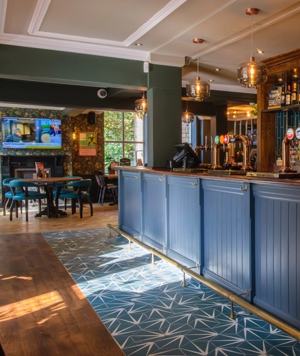 The interior bar and restaurant seating area with TV and fireplace at The Hare & Hounds.