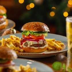 An advertising image of a 3 plated burger and fries dishes with a pint of lager available over Christmas at Venture Hotels.
