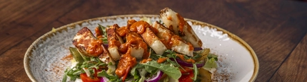 Halloumi salad served on a plate, sitting on a wooden table.