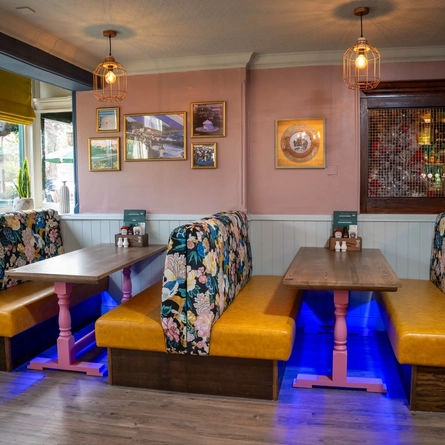 An interior restaurant seating area at The Grosvenor, with upholstered booth seats, and framed artwork on the wall.