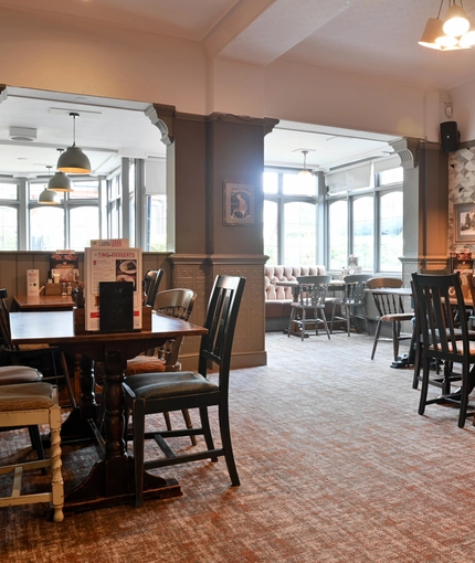 Interior dining area of a pub with a fireplace.