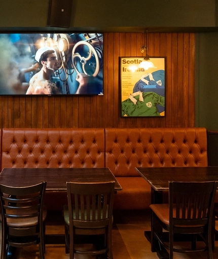 The interior seating area of Molly Malones, with upholstered seating, wooden tables, and TVs on the walls.