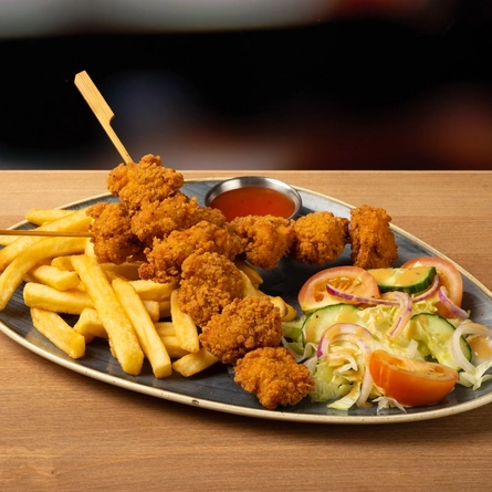 A plated kebab and fries on a wooden table.