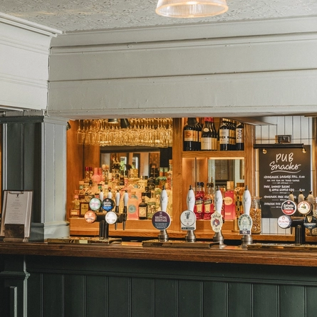 The bar inside The Inn On The Green, with framed artwork on the walls.