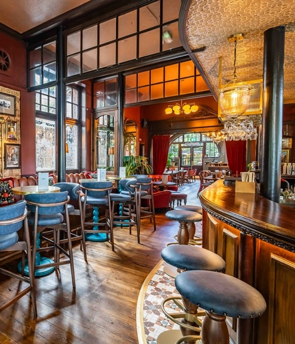 The interior bar with bar stool seating and restaurant seating area with tables, chairs, cushioned seating and exposed brickwork at The Duke Of Sussex.