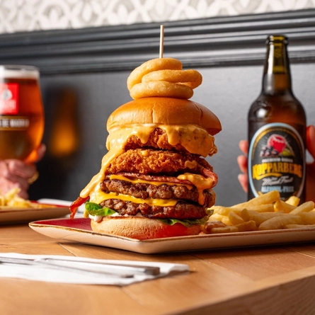 A close up image of a burger and various drinks sat on a table within the interior restaurant and seating area at a Hungry Horse venue.