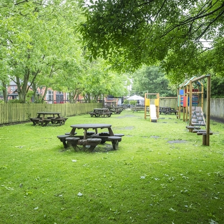 Exterior beer garden and playground of a pub with a seating area.