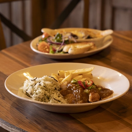 Two bowls of food sat on a wooden table in the seating restaurant area at the Dirty Bottles.