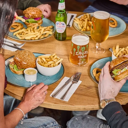 People eating burger and fries and drinking beer