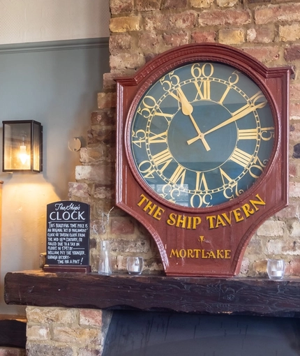 The brick fireplace and large clock inside The Ship in Mortlake.