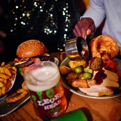 A image of gravy being poured over a roast meal within the interior restaurant and seating area of Greene King Pub venue.