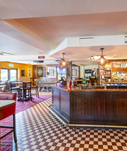 Interior dining area of a pub with a dining area, a pool table, a TV and a dartboard.