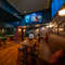 An interior restaurant seating area at the Scholars Arms; with TVs on the walls, padded bench seating, and two pool tables.