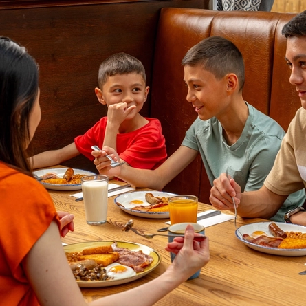 A family seated at an indoor table, enjoying breakfast.