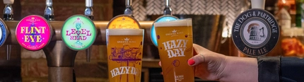 Two glasses of Hazy Day beer, on the bar.