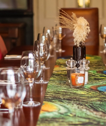 A close up image of the table decor featuring cutlery, glasses and peacock design table runner within one of the function rooms at The Vine.